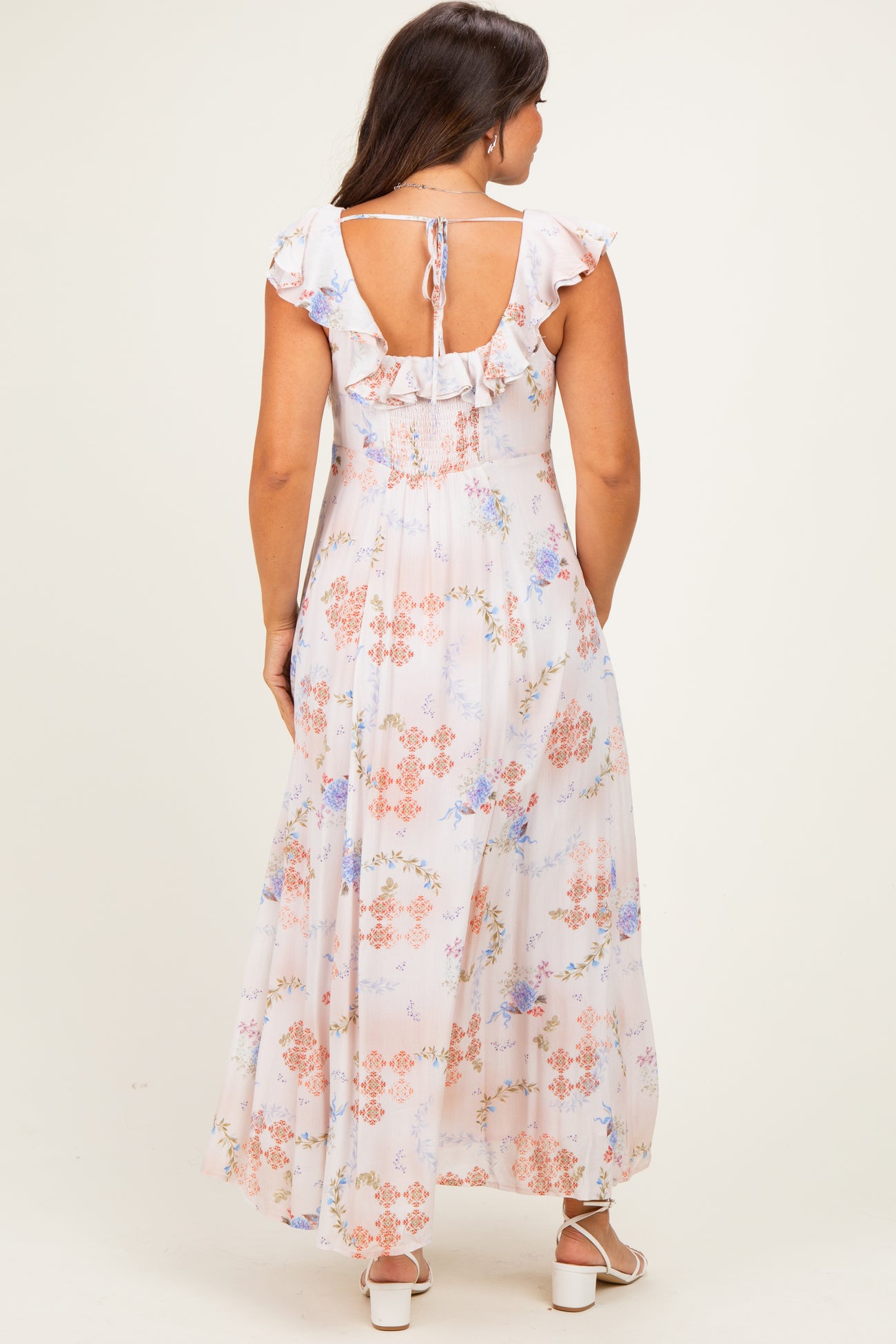 woman wearing a floral print maternity maxi dress with ruffled sleeves and an open back