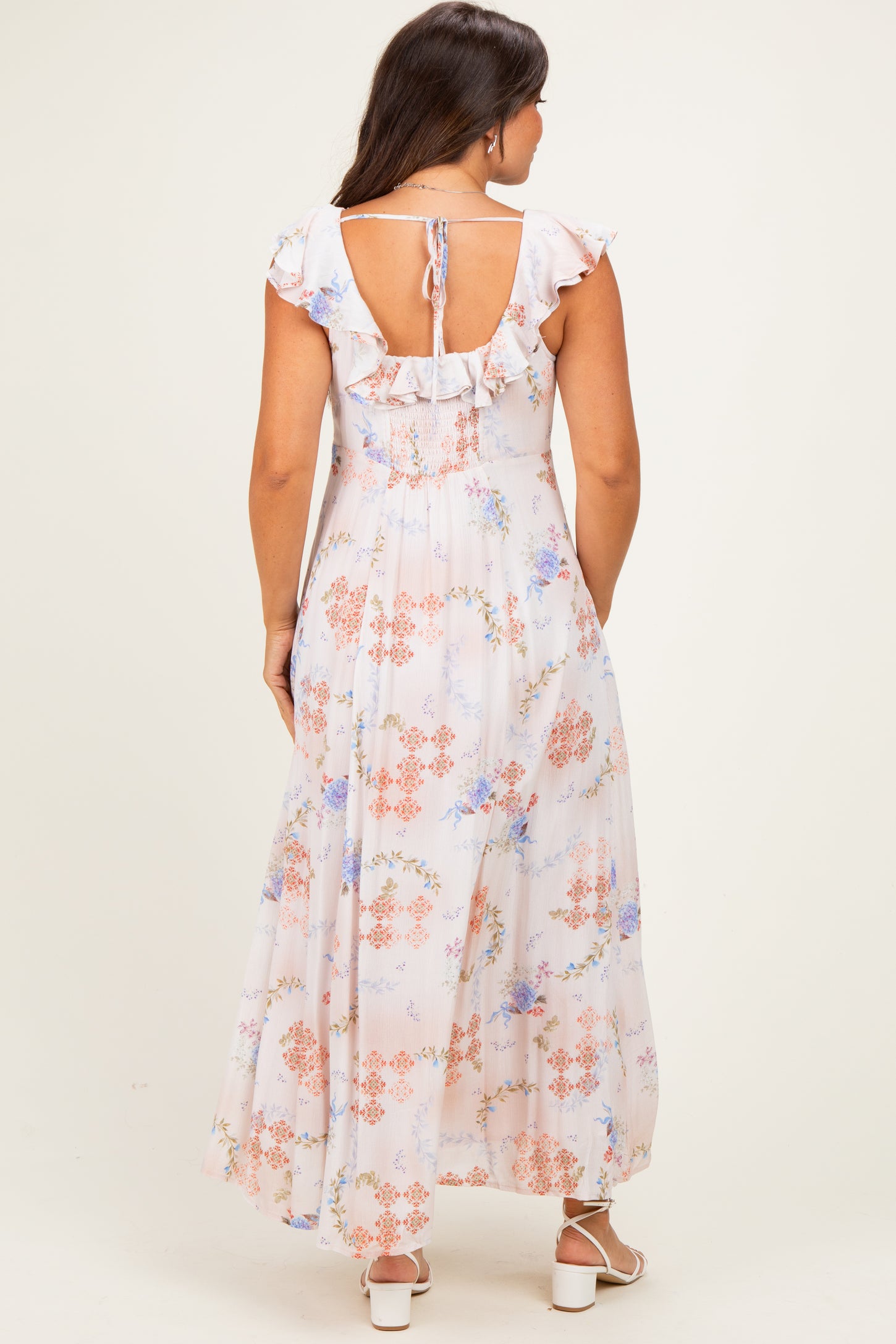 woman wearing a floral print maternity maxi dress with ruffled sleeves and an open back