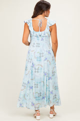 woman wearing a light blue floral maternity maxi dress with ruffle sleeves and a tie back detail