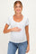woman wearing a white maternity top with blue floral print and short sleeves, cradling her baby bump