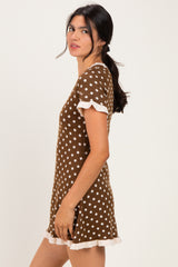 woman wearing a brown polka dot dress with white ruffled sleeves and hemline, posing sideways