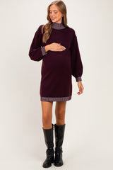 woman wearing a burgundy maternity sweater dress with striped collar and sleeves, holding her baby bump