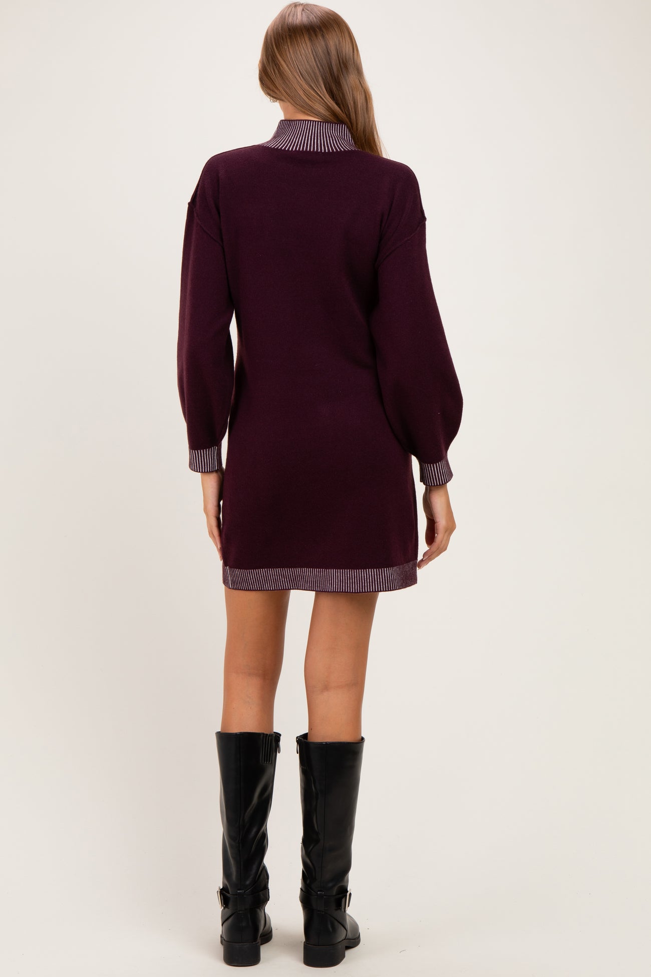 woman wearing a burgundy maternity sweater dress with striped collar and cuffs, seen from the back