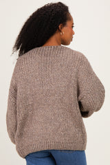 woman wearing a cozy taupe oversized knit sweater, showing the back view