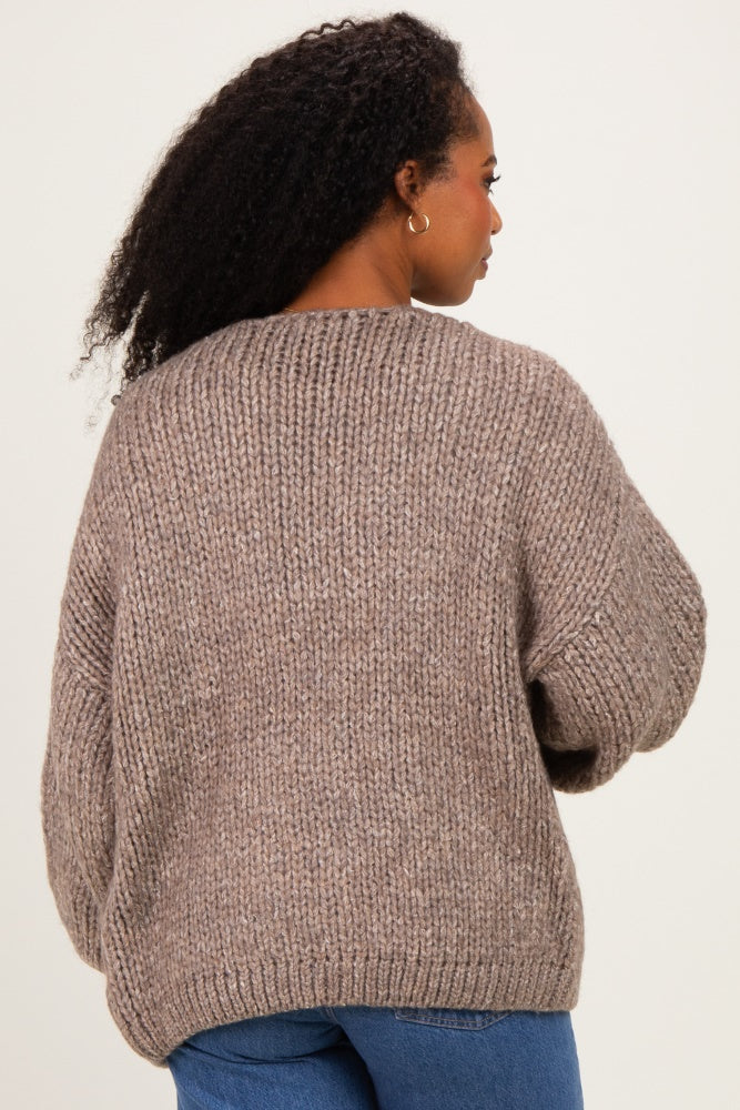 woman wearing a cozy taupe oversized knit sweater, showing the back view