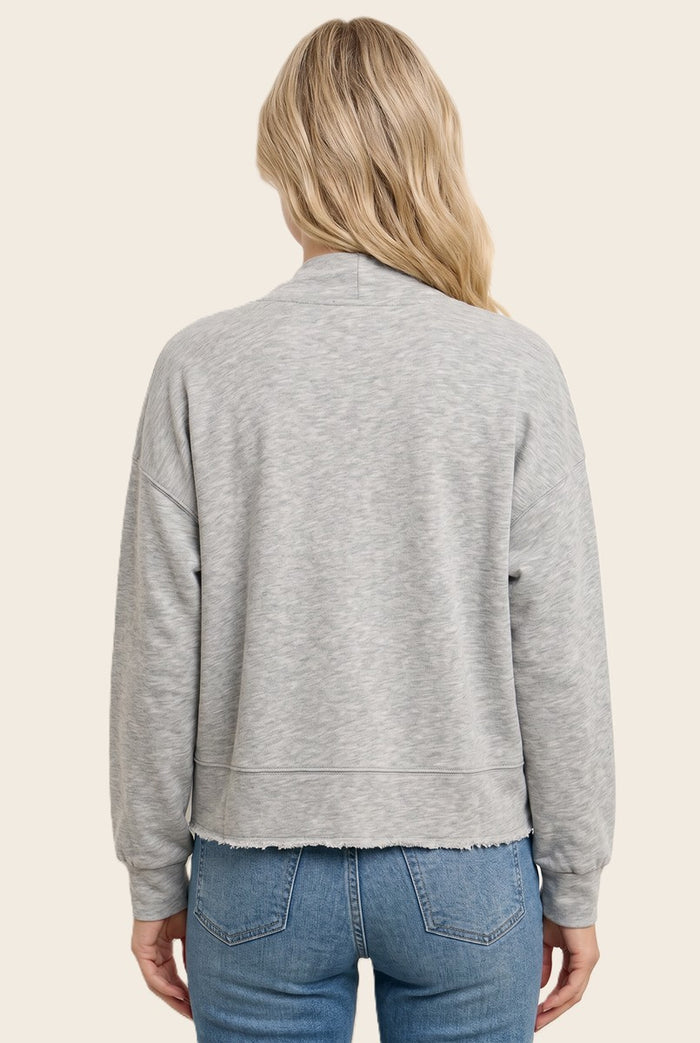 woman wearing a light gray cropped sweatshirt with a raw hem, styled with blue jeans