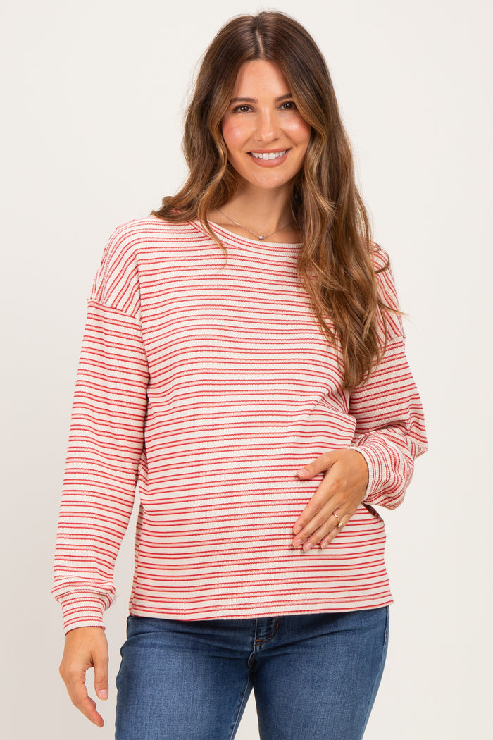woman wearing a red and white striped long sleeve maternity top and holding her baby bump