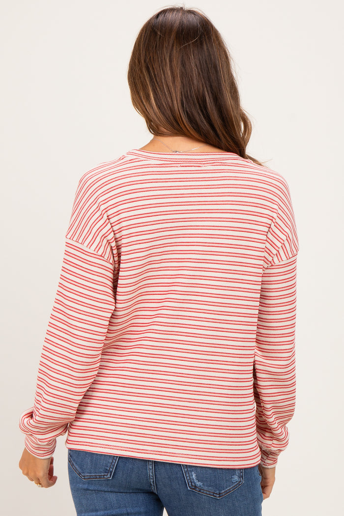 woman wearing a red and white striped maternity top with long sleeves, showing her back and styled with jeans