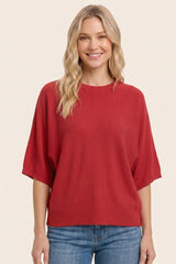 woman wearing a red oversized short sleeve sweater with a relaxed fit and smiling
