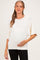 woman wearing a cream oversized maternity sweater and gently cradling her baby bump