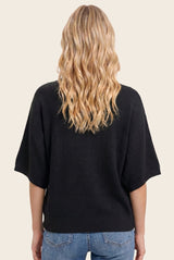 woman wearing a black oversized knit sweater with wide sleeves and a relaxed fit