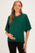 woman wearing a green oversized maternity sweater and holding her baby bump