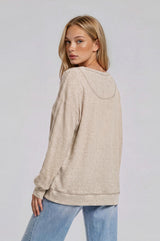 woman wearing a beige loose-fitting long sleeve hoodie with a textured fabric and a relaxed silhouette