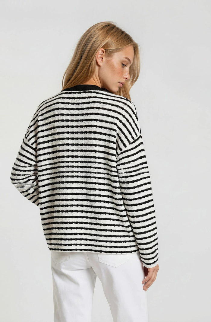 woman wearing a black and white striped sweater with a relaxed fit, view of the back with long sleeves and a round neckline