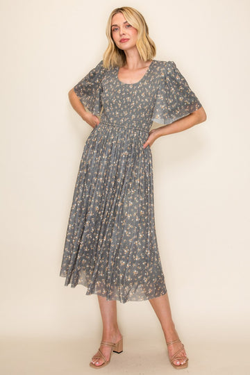 woman wearing a gray floral midi dress with short flutter sleeves and a fitted bodice