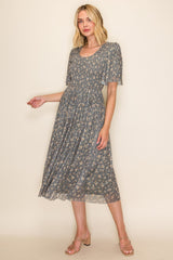 woman wearing a grey floral midi dress with short flutter sleeves and a flowing skirt