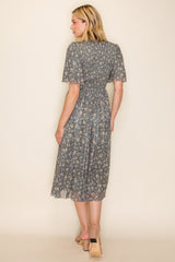 woman wearing a teal floral midi dress with short sleeves and a cinched waist, showing the back view