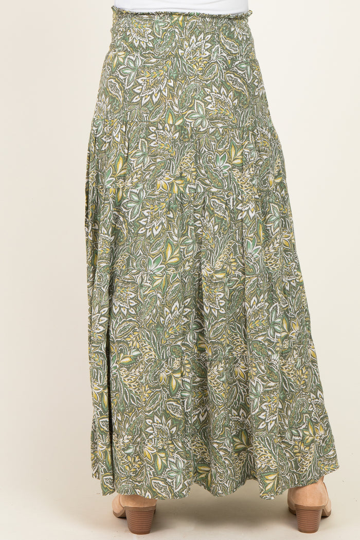 woman wearing a green floral maternity maxi skirt with a flowy design, showcasing a gathered waistband and tiered style