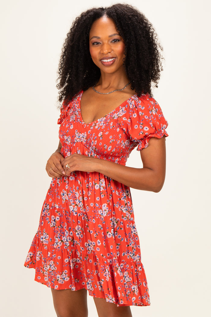 woman wearing a vibrant red floral print short dress with puff sleeves and a tiered skirt
