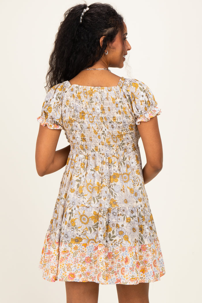 woman wearing a floral print maternity dress with short puff sleeves and a smocked bodice, showing a baby bump