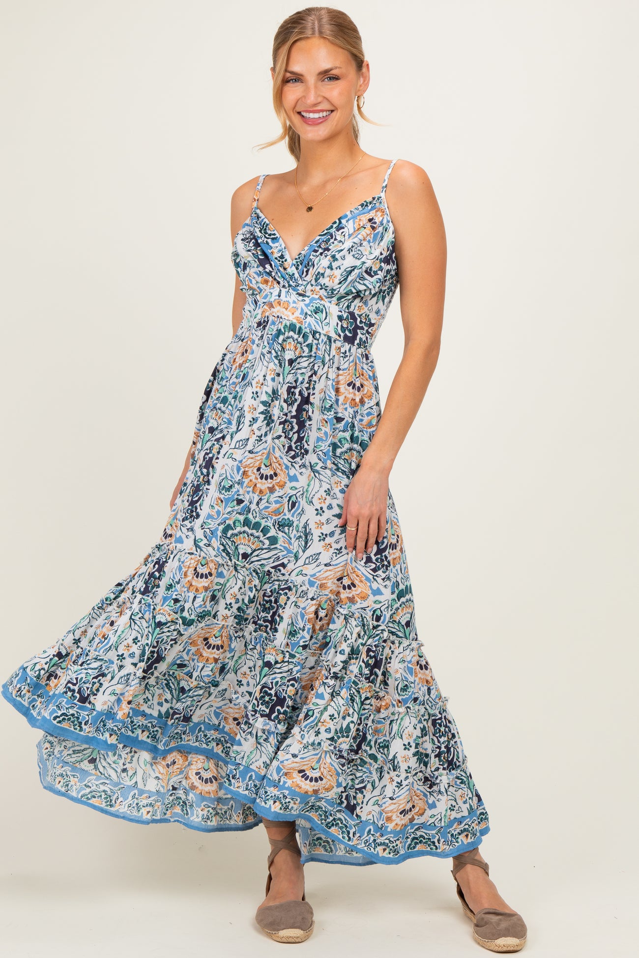 woman wearing a blue and white floral maxi dress with adjustable straps and a flowing skirt