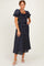 woman wearing a navy blue polka dot midi dress with puff sleeves and a smocked bodice