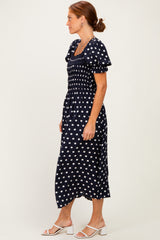 woman wearing a navy blue polka dot midi dress with puff sleeves and a smocked bodice