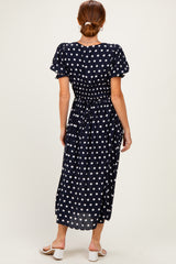 woman wearing a navy blue polka dot midi dress with puff sleeves and a cinched waist, viewed from the back