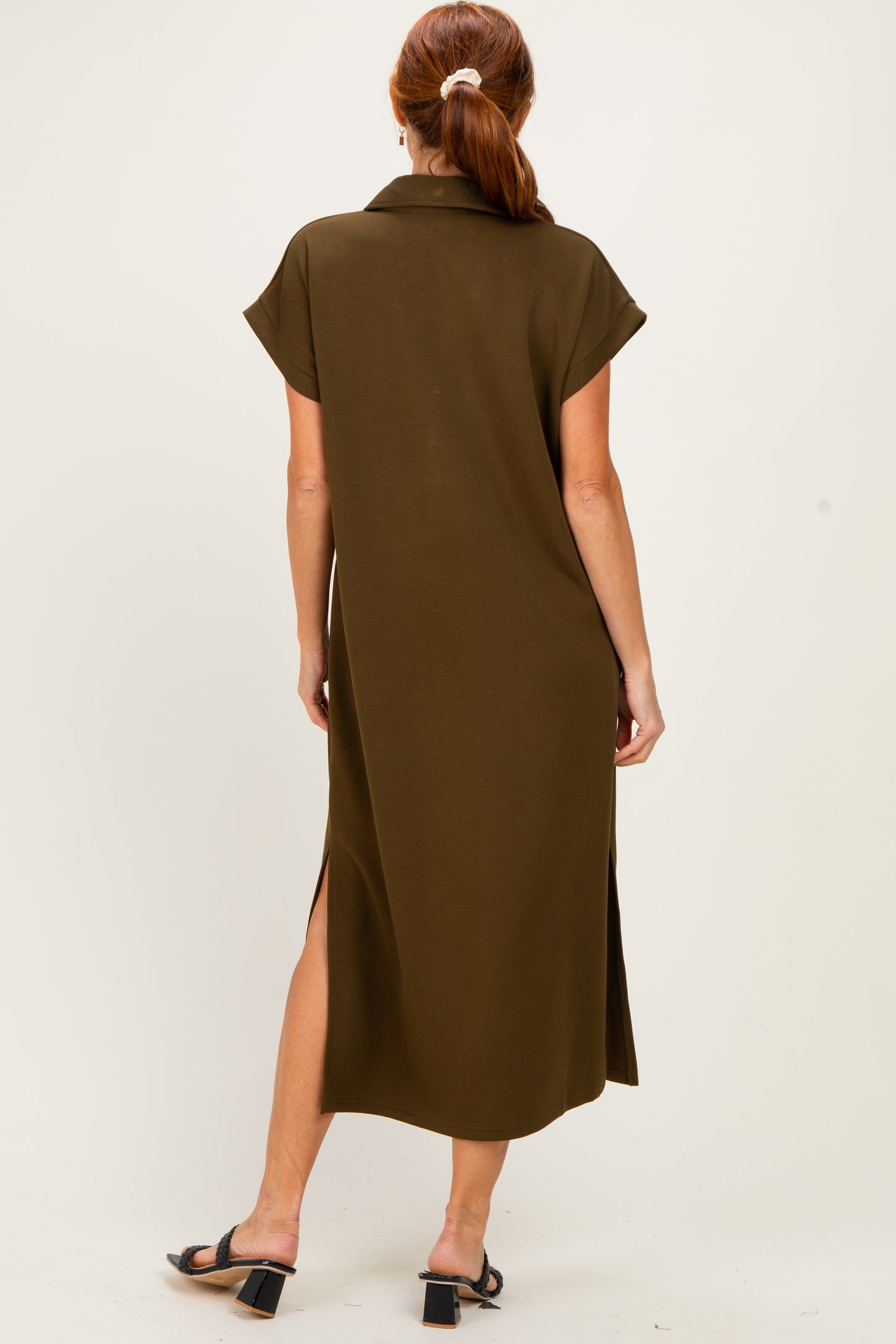 woman wearing an olive green midi shirt dress with short sleeves and side slits, viewed from the back