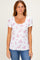 woman wearing a white short sleeve top with pink floral print and a scoop neckline, paired with blue jeans