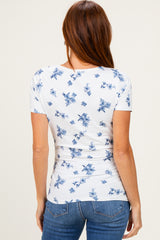 woman wearing a white short sleeve top with blue floral print, view from the back, paired with denim jeans