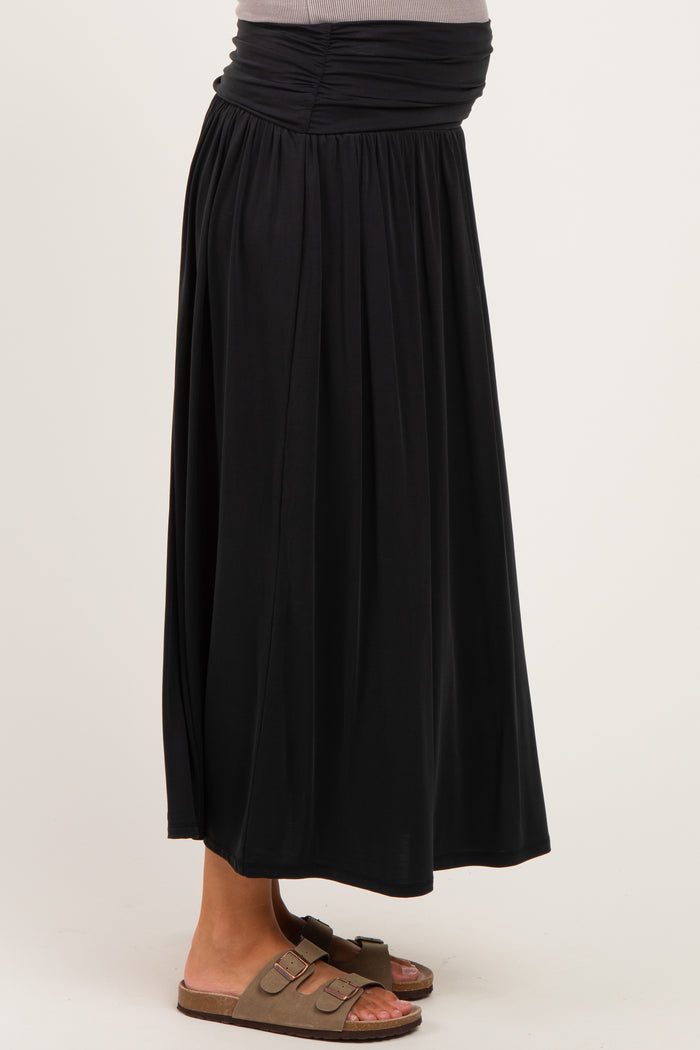 maternity wear black maxi skirt with a gathered waistband, model showing a baby bump, paired with brown sandals