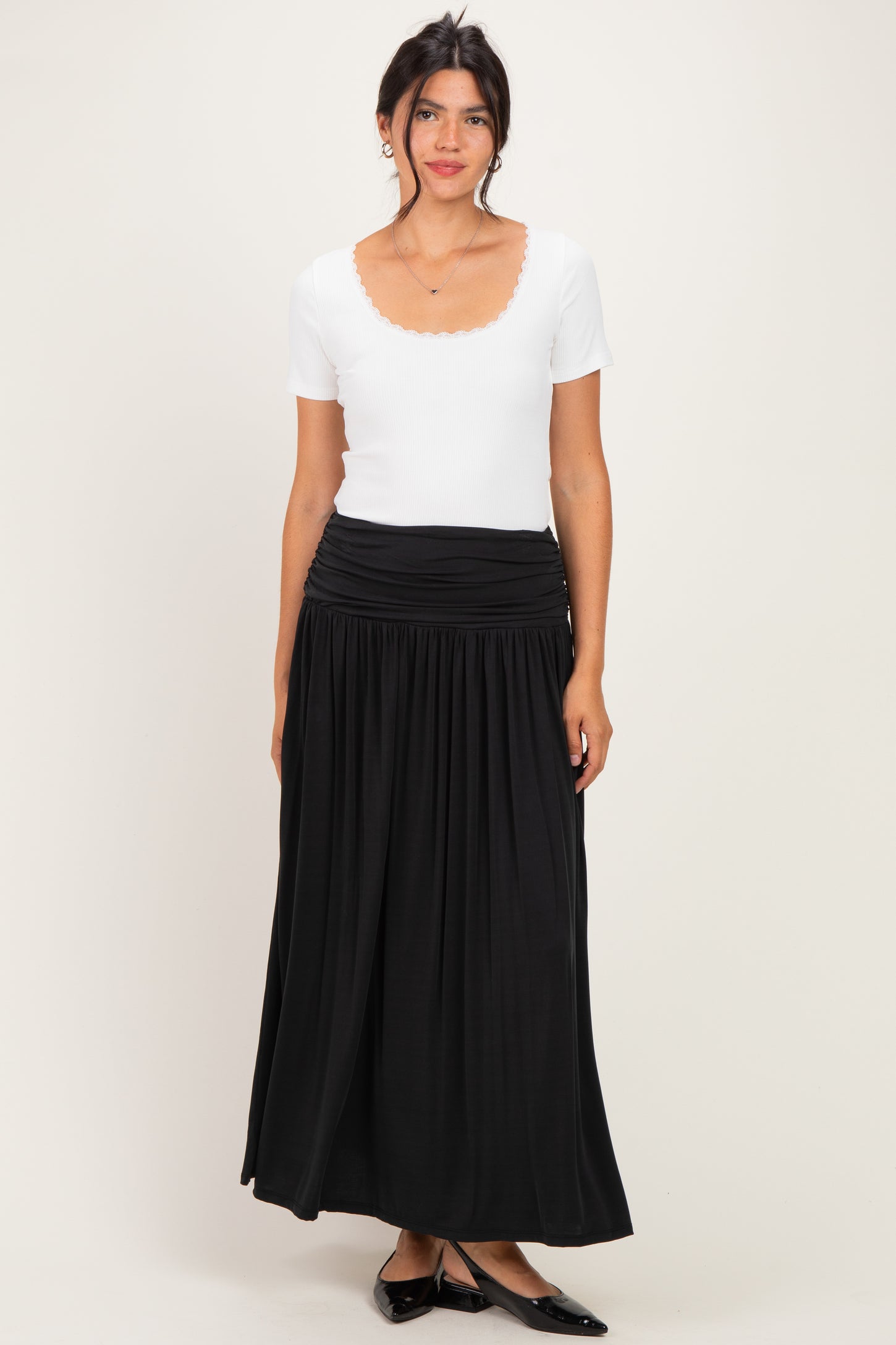 woman wearing a white short sleeve top and a black maxi skirt with a gathered waistband