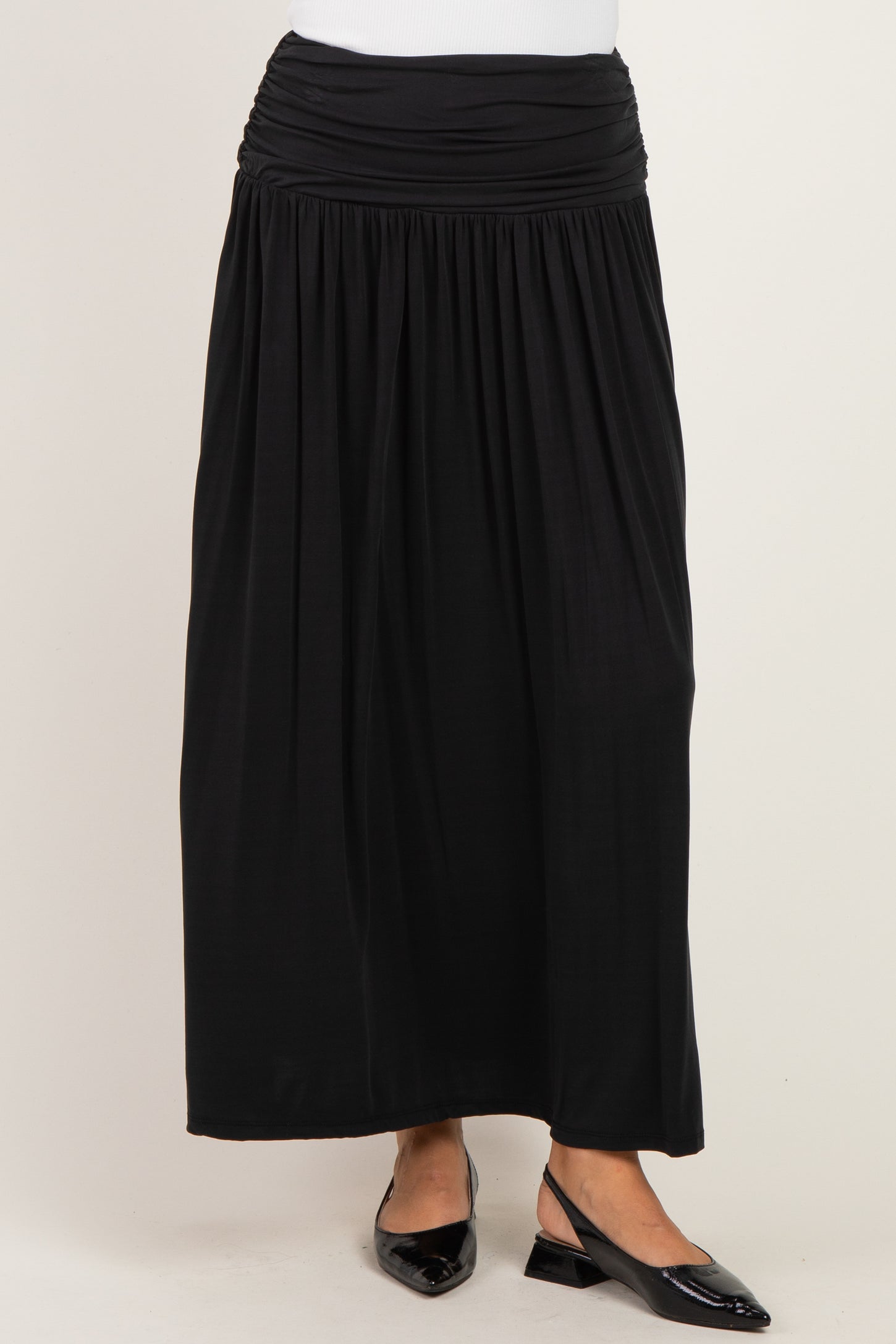 woman wearing a black maxi skirt with a ruched waistband and flat shoes