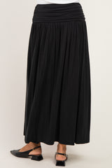 woman wearing a black maxi skirt with a gathered waistband and flowing design, facing away from the camera
