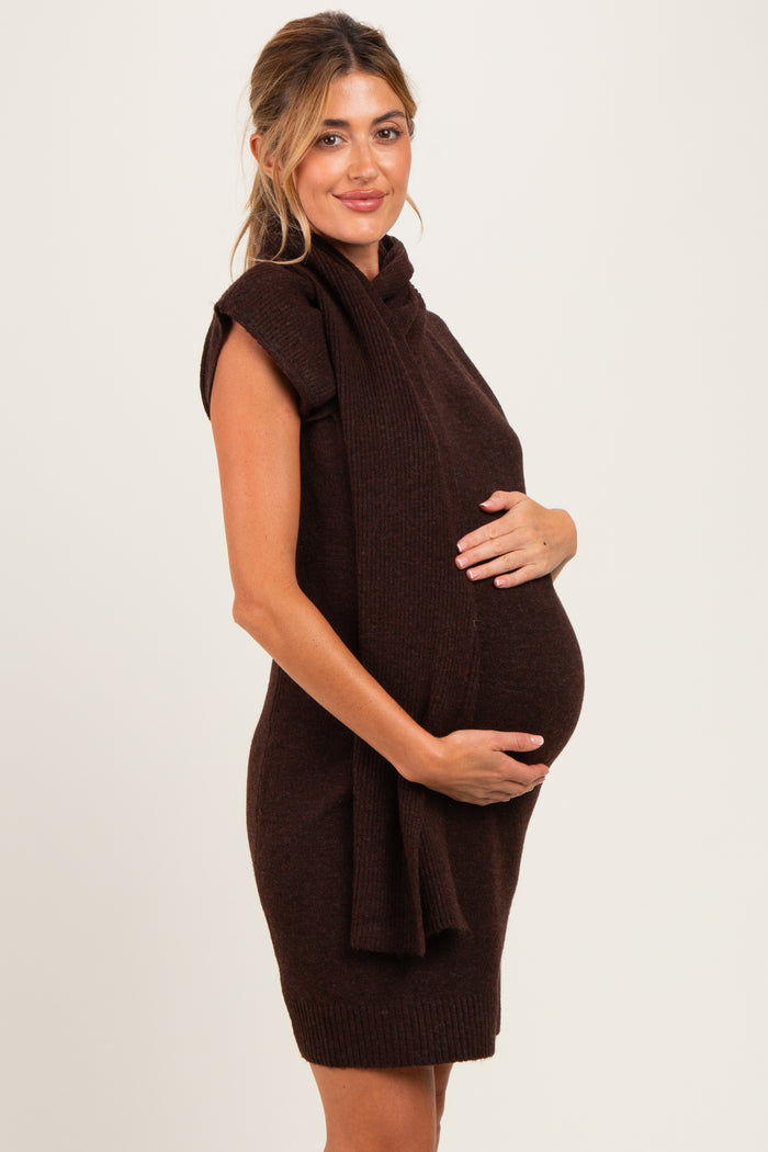 woman wearing a chocolate brown sleeveless maternity sweater dress and holding her baby bump