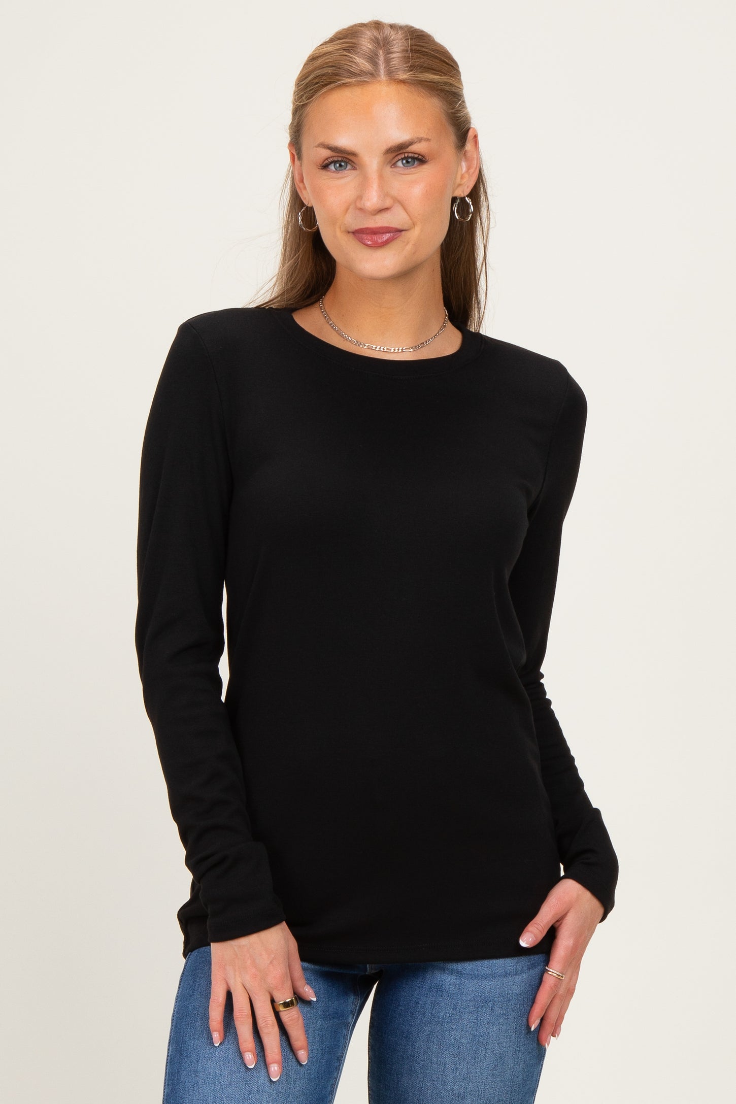 woman wearing a black long sleeve top with a round neckline and jeans