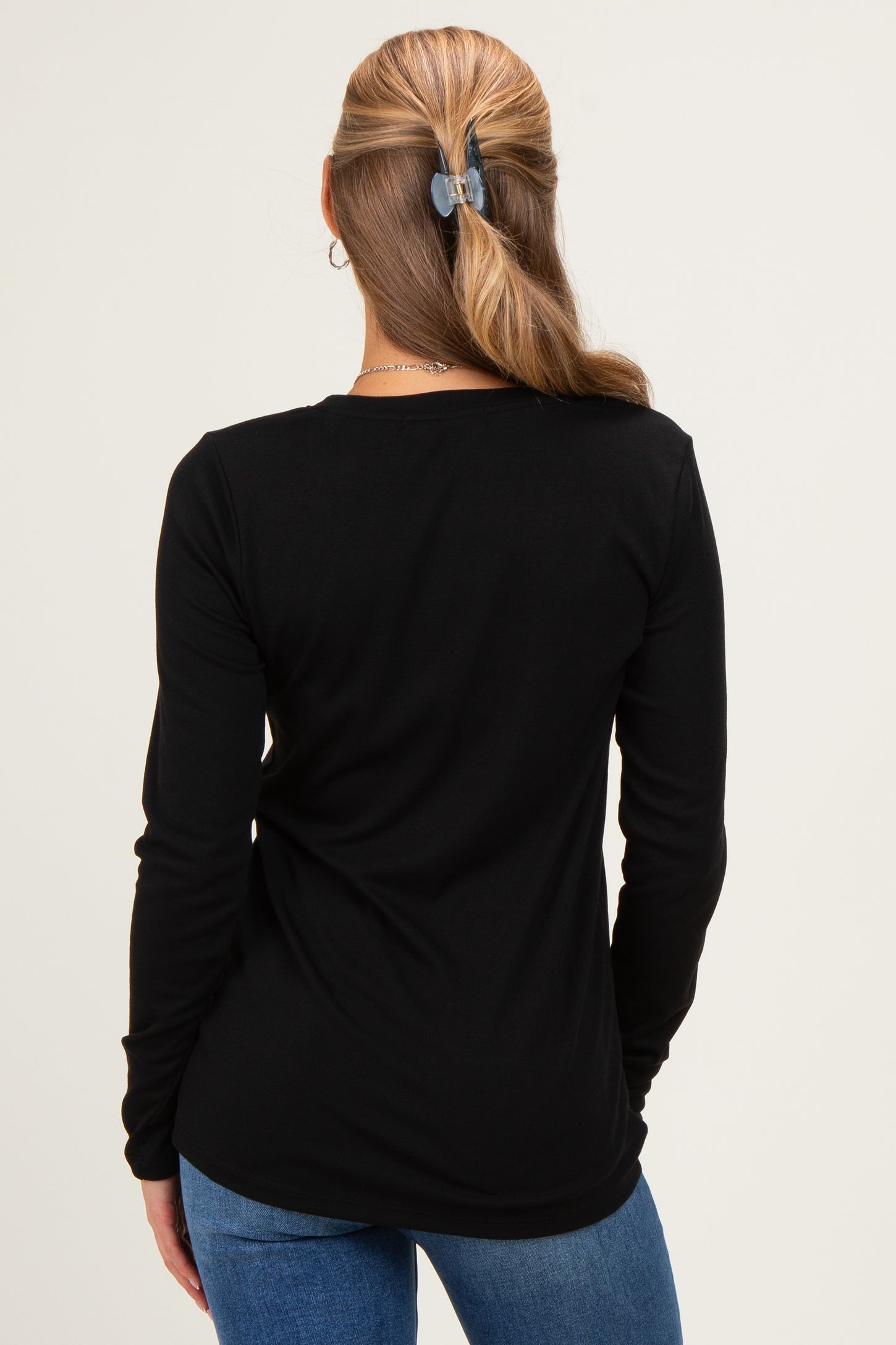 woman wearing a black long sleeve top, viewed from the back, paired with blue jeans