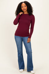 woman wearing a burgundy long sleeve top paired with light blue flared jeans and white sneakers