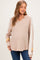 woman wearing a beige maternity wear v-neck sweater with taupe and mustard stripes and a visible baby bump