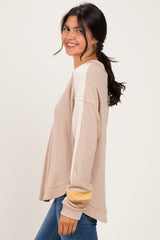 woman wearing a beige long sleeve sweater with color block sleeves and smiling at the camera
