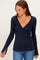 woman wearing a navy blue long sleeve wrap top with a v-neck and side slits, paired with blue jeans