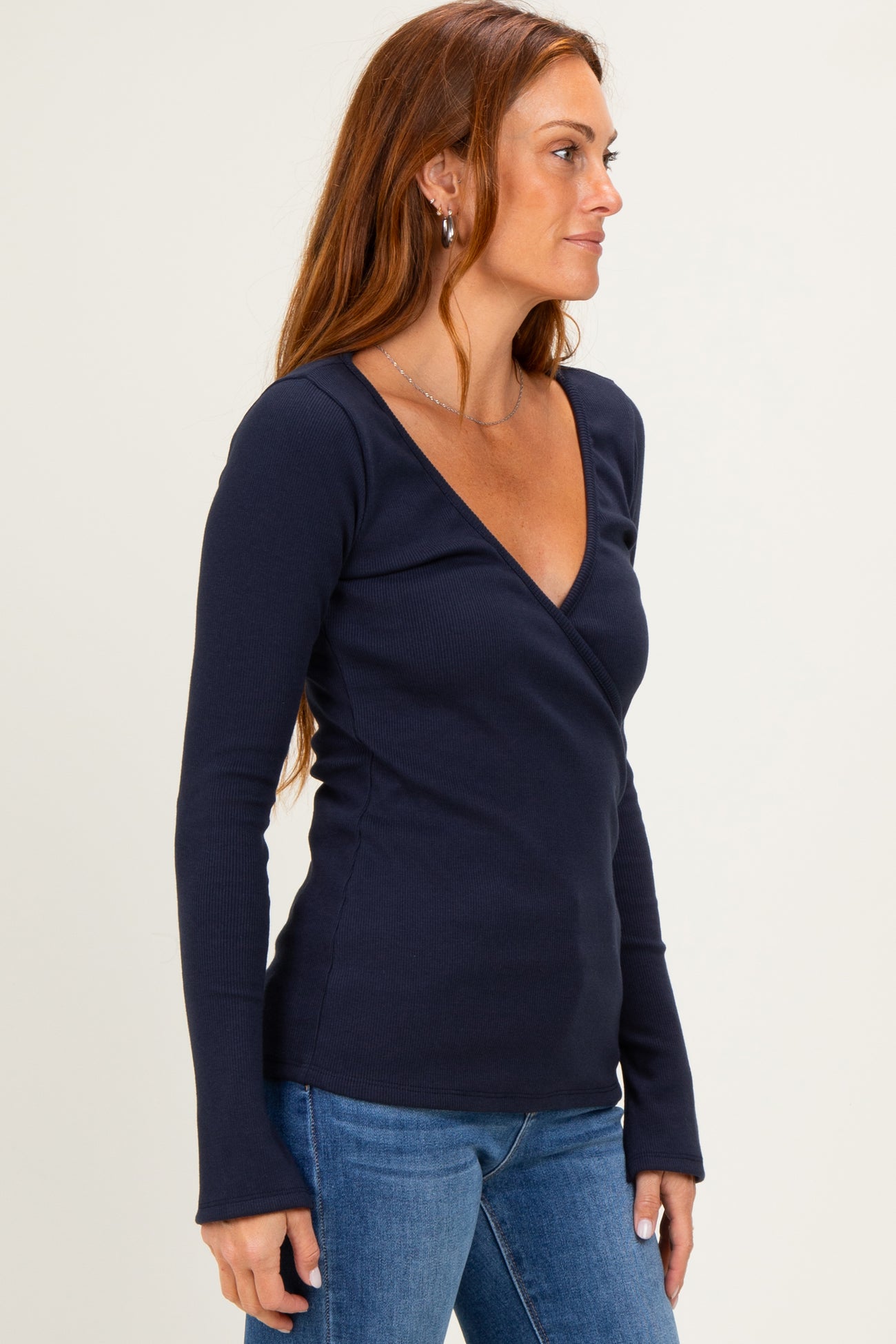 woman wearing a navy blue long sleeve wrap top paired with light blue jeans