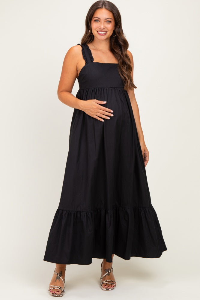 woman wearing a black maternity maxi dress with ruffled straps and a flowing skirt, holding her baby bump
