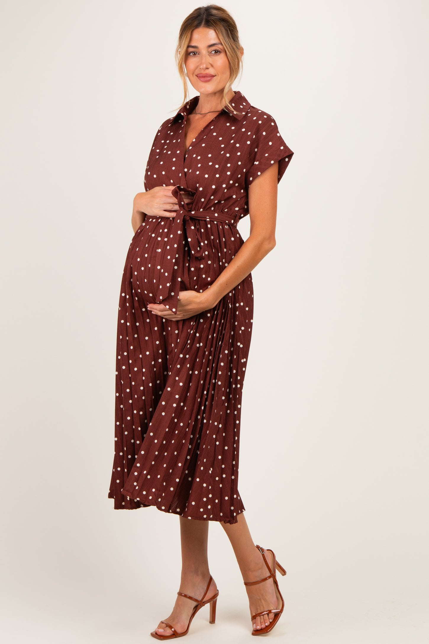woman wearing a brown maternity dress with white polka dots and a tie waist, showcasing her baby bump