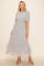 woman wearing a light grey floral maxi dress with puff sleeves and a tiered skirt, paired with strappy sandals