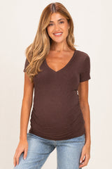 woman wearing a dark brown maternity v-neck top with ruching on the sides and a visible baby bump