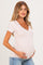 woman wearing a light beige v-neck maternity top and holding her baby bump