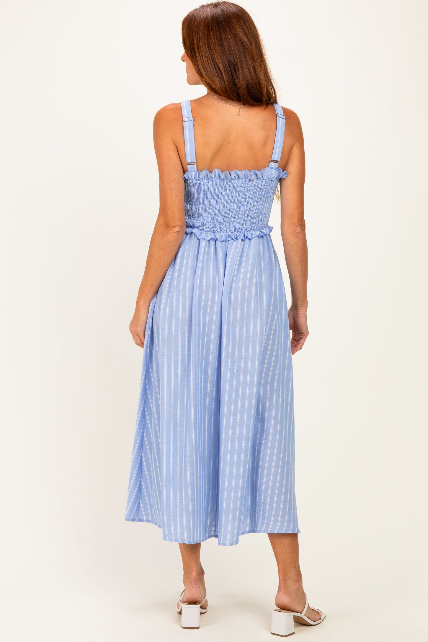 woman wearing a light blue striped midi dress with a smocked bodice and adjustable straps, showing the back view