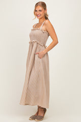 woman wearing a beige and white striped maxi dress with a smocked bodice and ruffled straps, posing with hands in pockets